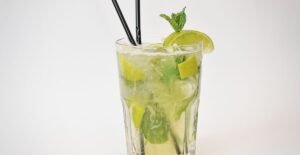 A refreshing glass of green Pudina Sharbat garnished with fresh mint leaves, served with ice cubes, showcasing its vibrant, minty color.