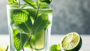 Fresh mint leaves and lime wedges in a glass, the first step to making the best virgin mojito