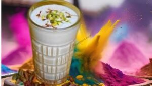 A beautifully prepared glass of Holi special thandai, garnished with rose petals, almonds, and pistachios, surrounded by vibrant Holi colors and festive decorations.